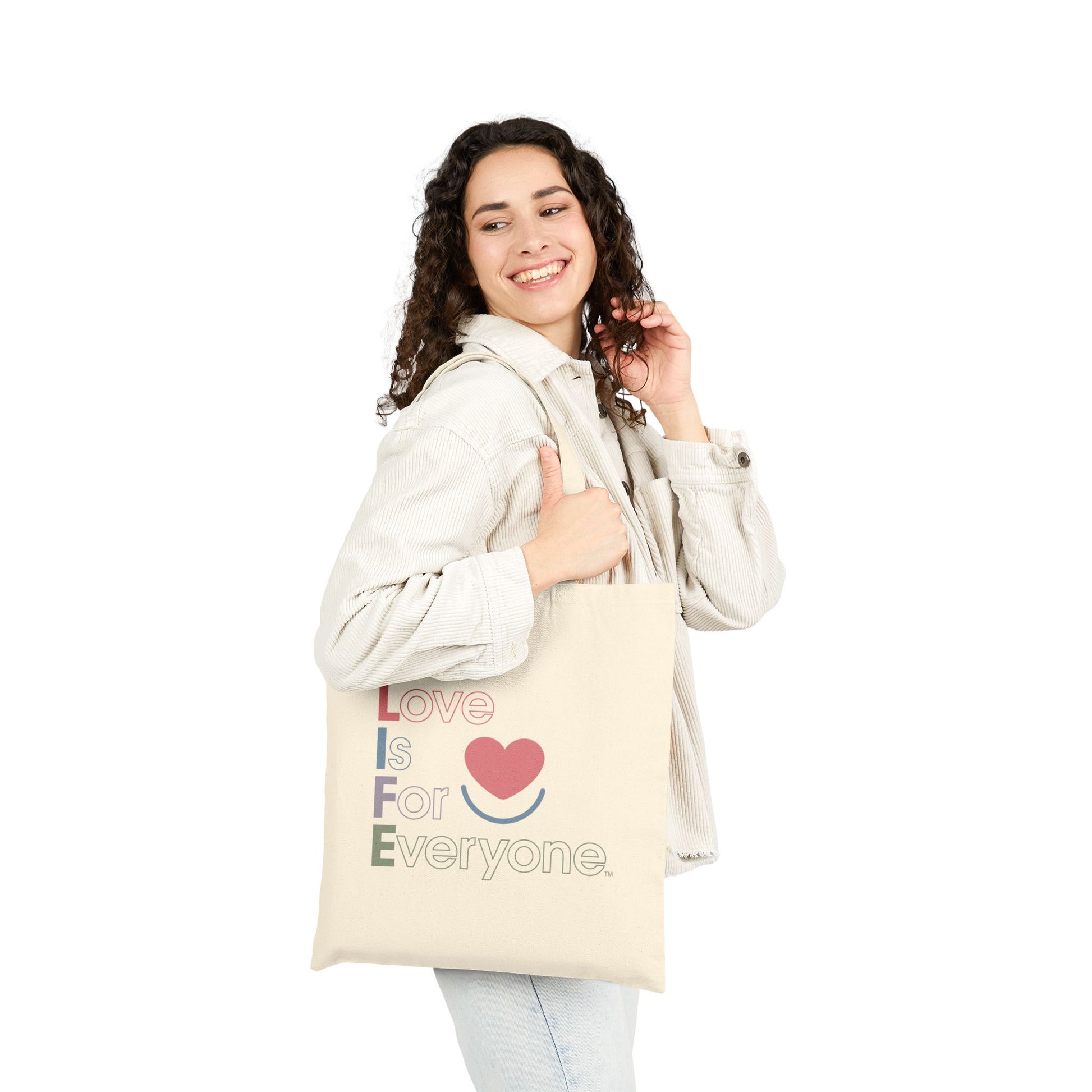 Woman carrying natural canvas L.I.F.E. Color Pop tote with multi-color "Love is for Everyone" graphic.