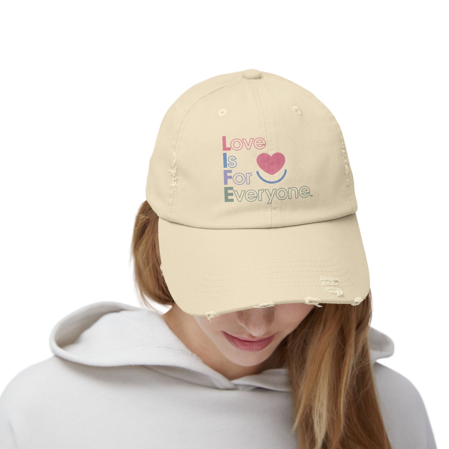 Woman wearing stone L.I.F.E. Color Pop distressed cotton twill dad hat with printed vertical "Love is for Everyone".