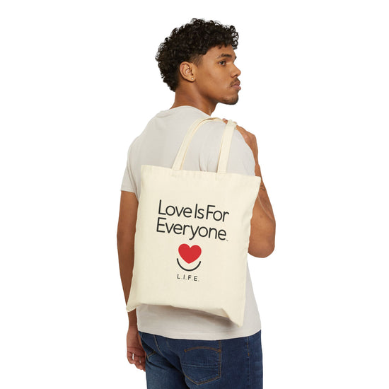 Man carrying natural canvas L.I.F.E. Everyday tote bag with "Love is for Everyone" graphic.