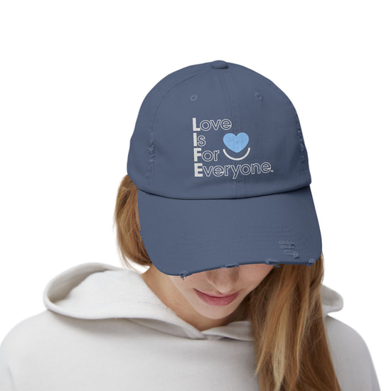 Woman wearing blue L.I.F.E. Colorful Expressions distressed cotton twill dad hat with printed vertical "Love is for Everyone".