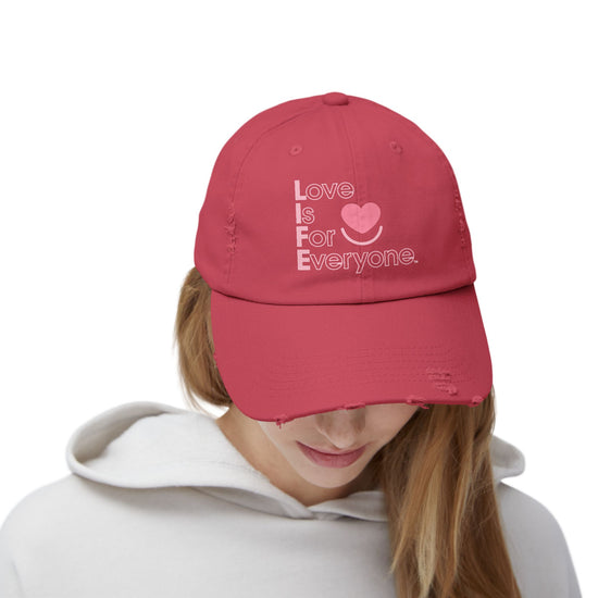 Woman wearing red L.I.F.E. Colorful Expressions distressed cotton twill dad hat with printed vertical "Love is for Everyone".