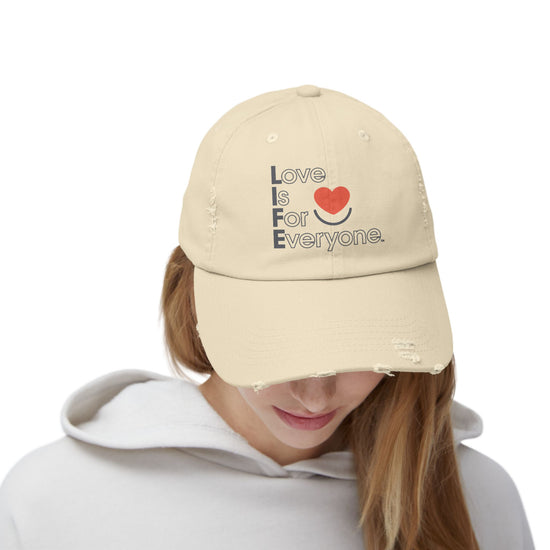 Woman wearing stone L.I.F.E. Colorful Expressions distressed cotton twill dad hat with printed vertical "Love is for Everyone".