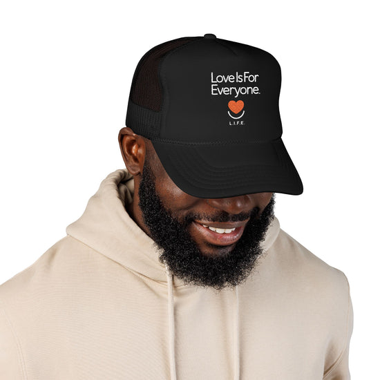Man wearing black L.I.F.E. embroidered trucker hat with positive message "Love is for Everyone".