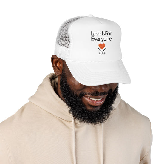 Man wearing white L.I.F.E. embroidered trucker hat with smiling heart logo.