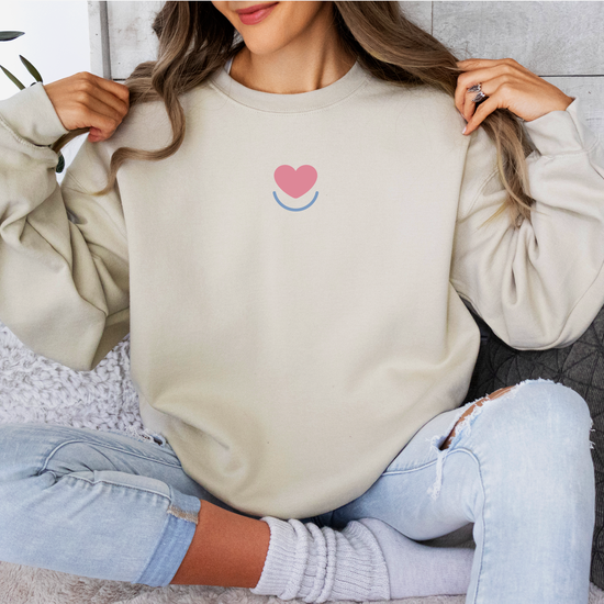 Woman wearing sand women's Color Pop crewneck sweatshirt, front view with small chest print.