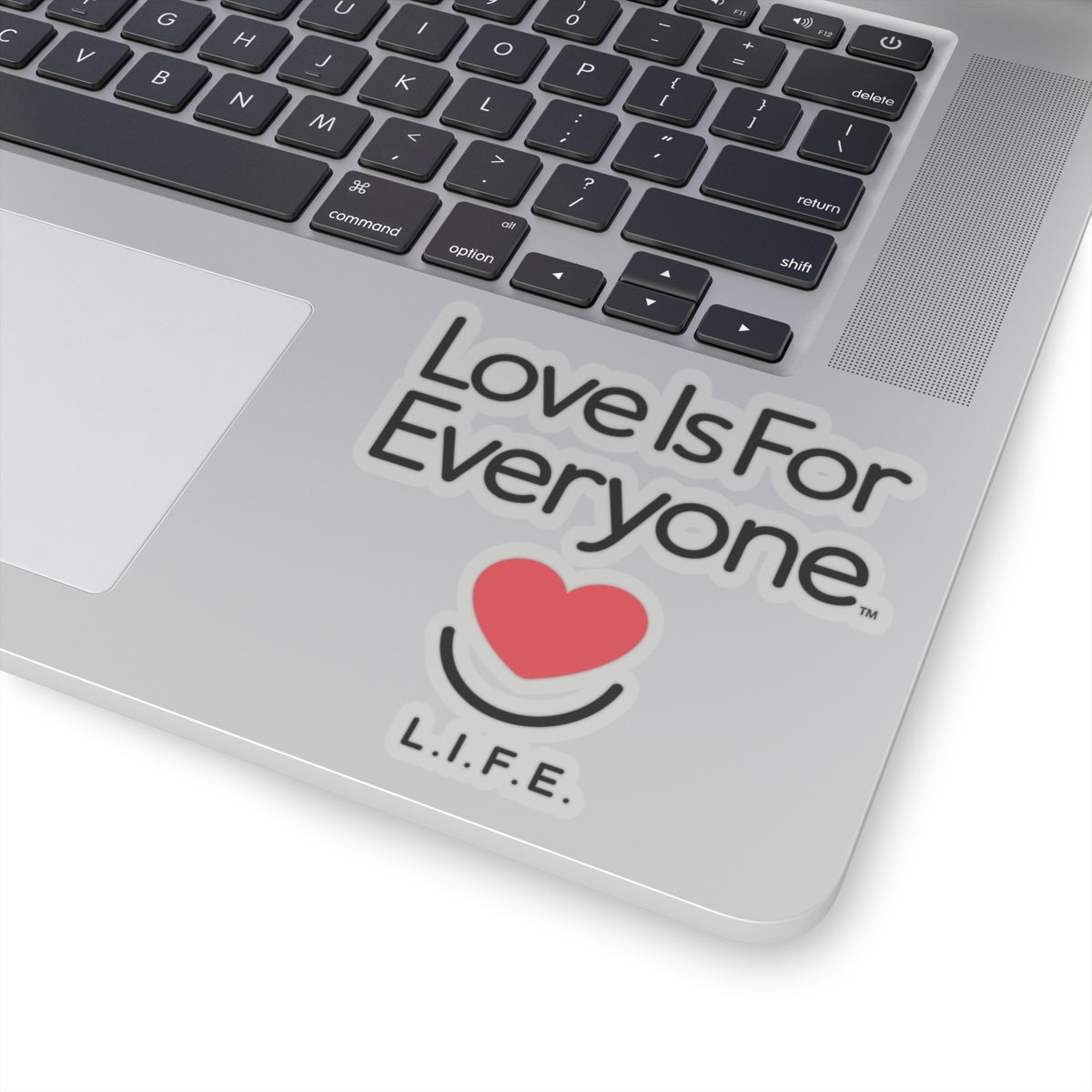 Transparent L.I.F.E. 4x4 "love is for Everyone" vinyl sticker on laptop corner with heart smile logo. 
