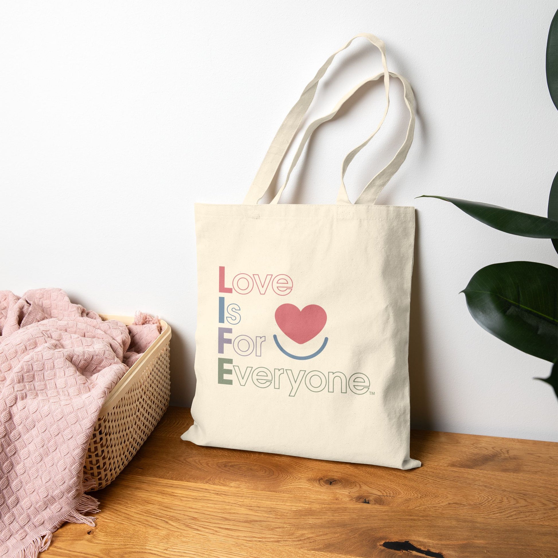 Natural Canvas L.I.F.E. Color Pop tote on tabletop showing statement print and flat corners.