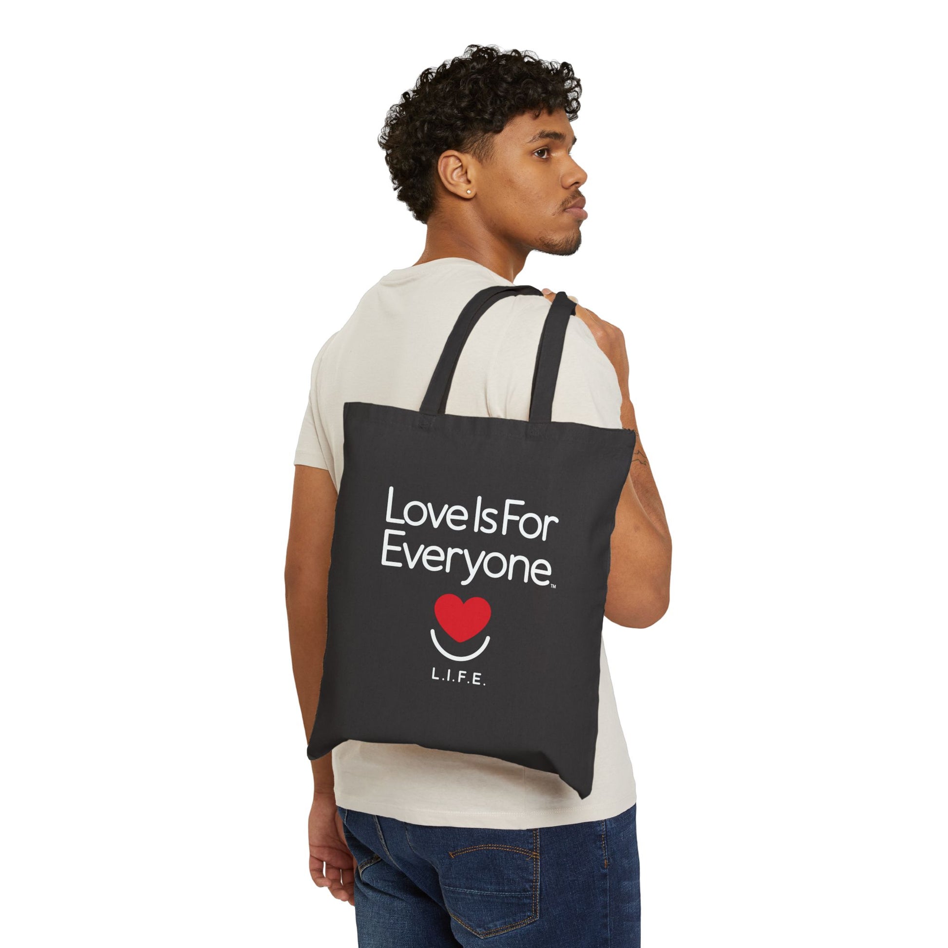 Man carrying black Everyday L.I.F.E. canvas tote over shoulder, casual outfit. 