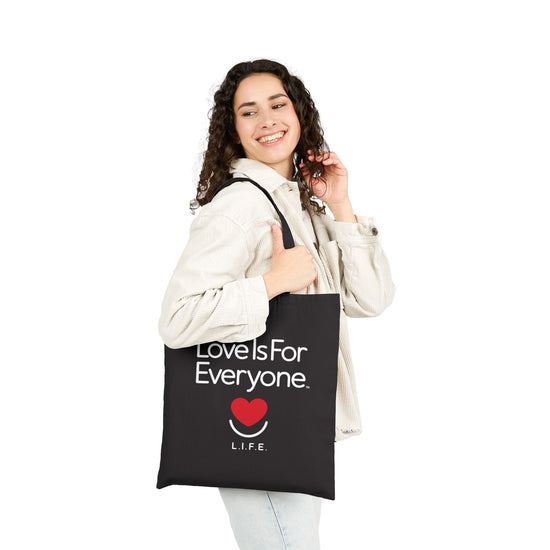 Woman holding black Everyday L.I.F.E. tote against light outfit, everyday look. 