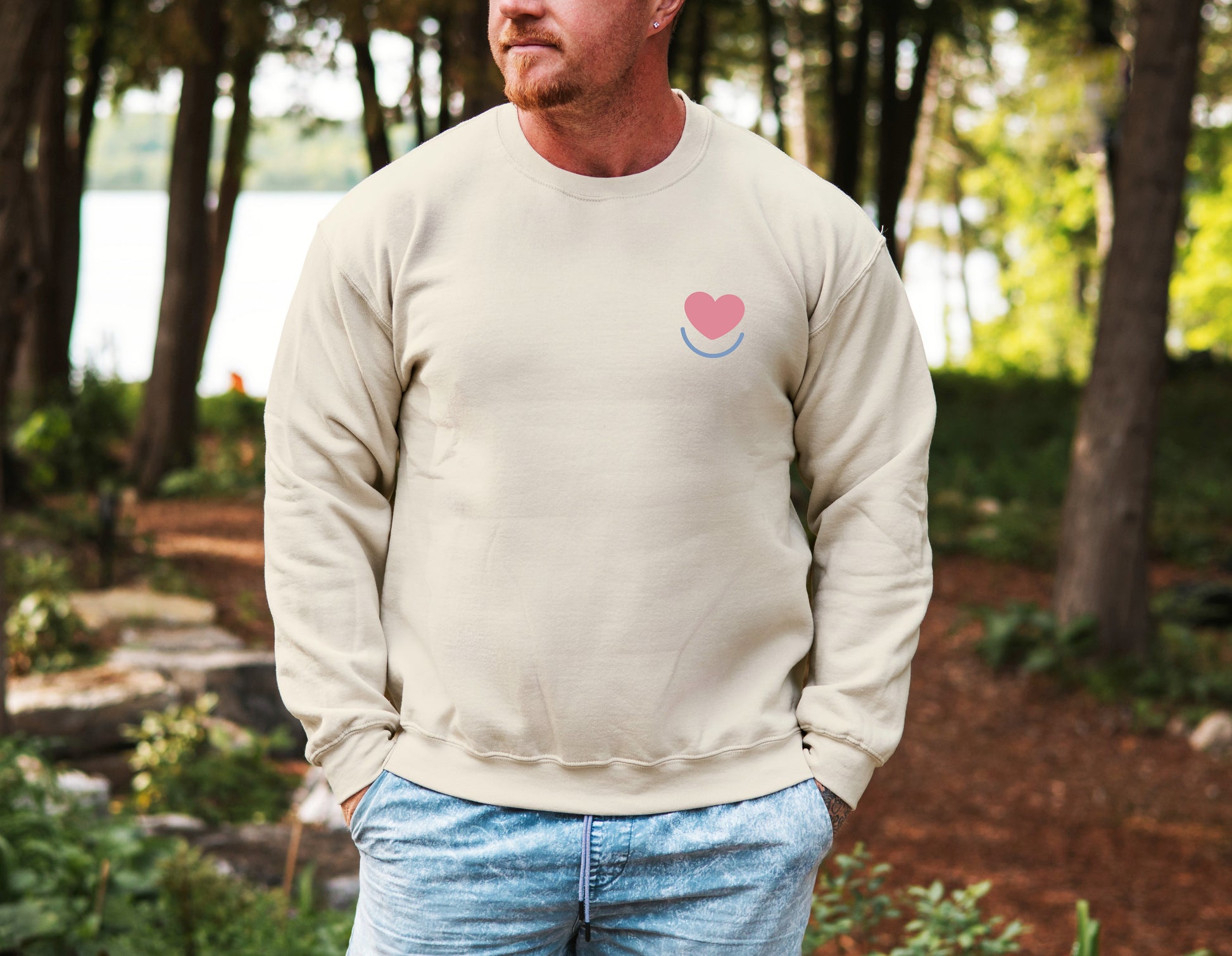 Man wearing men's Color Pop sand  crewneck, front view with heart smile logo.