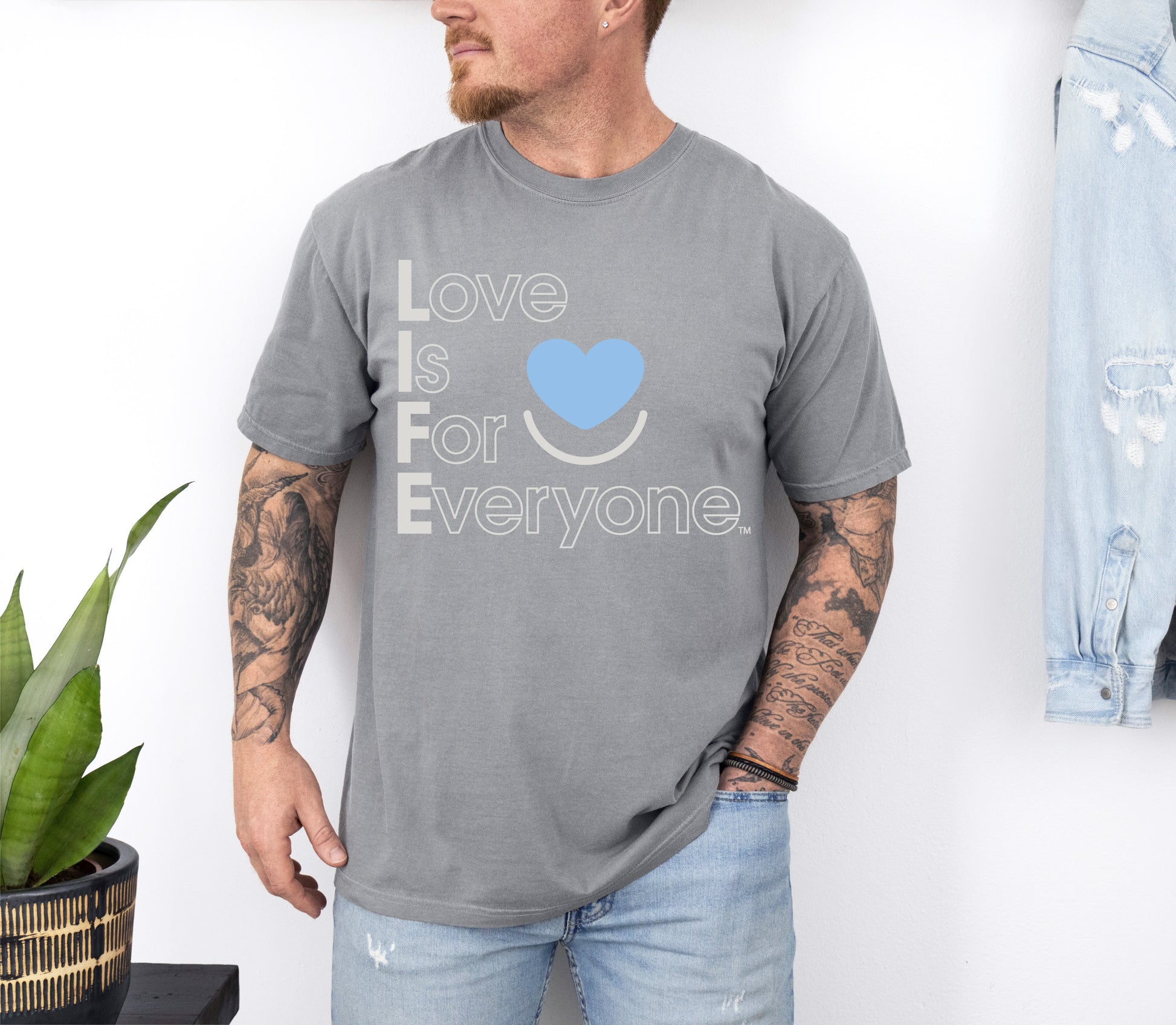 Man wearing Comfort Colors gray t-shirt with 'Love is for Everyone' text and blue heart symbol.