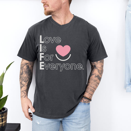 Man wearing Comfort Colors pepper Tee with vertical subtle message of Love is for Everyone. 