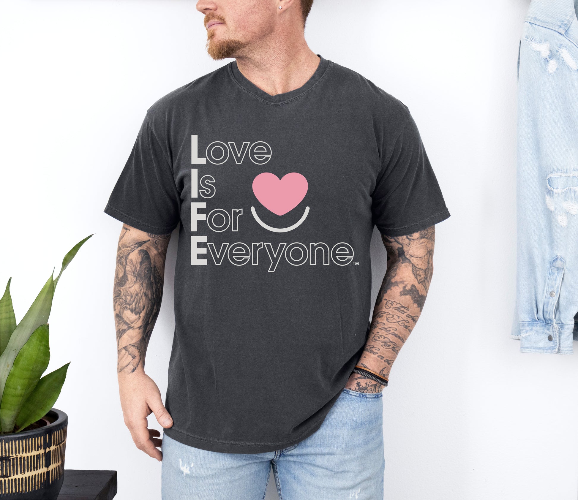 Man wearing Comfort Colors pepper Tee with vertical subtle message of Love is for Everyone. 