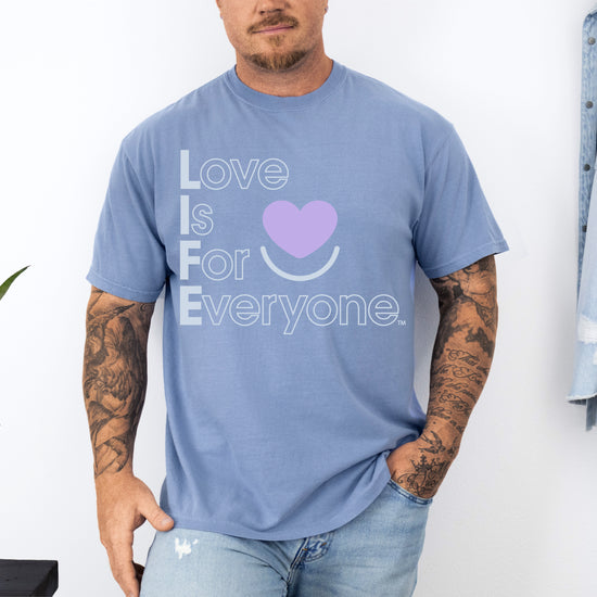 Man wearing Colorful Expressions washed denim Tee with “Love is for Everyone” postive message and heart smile