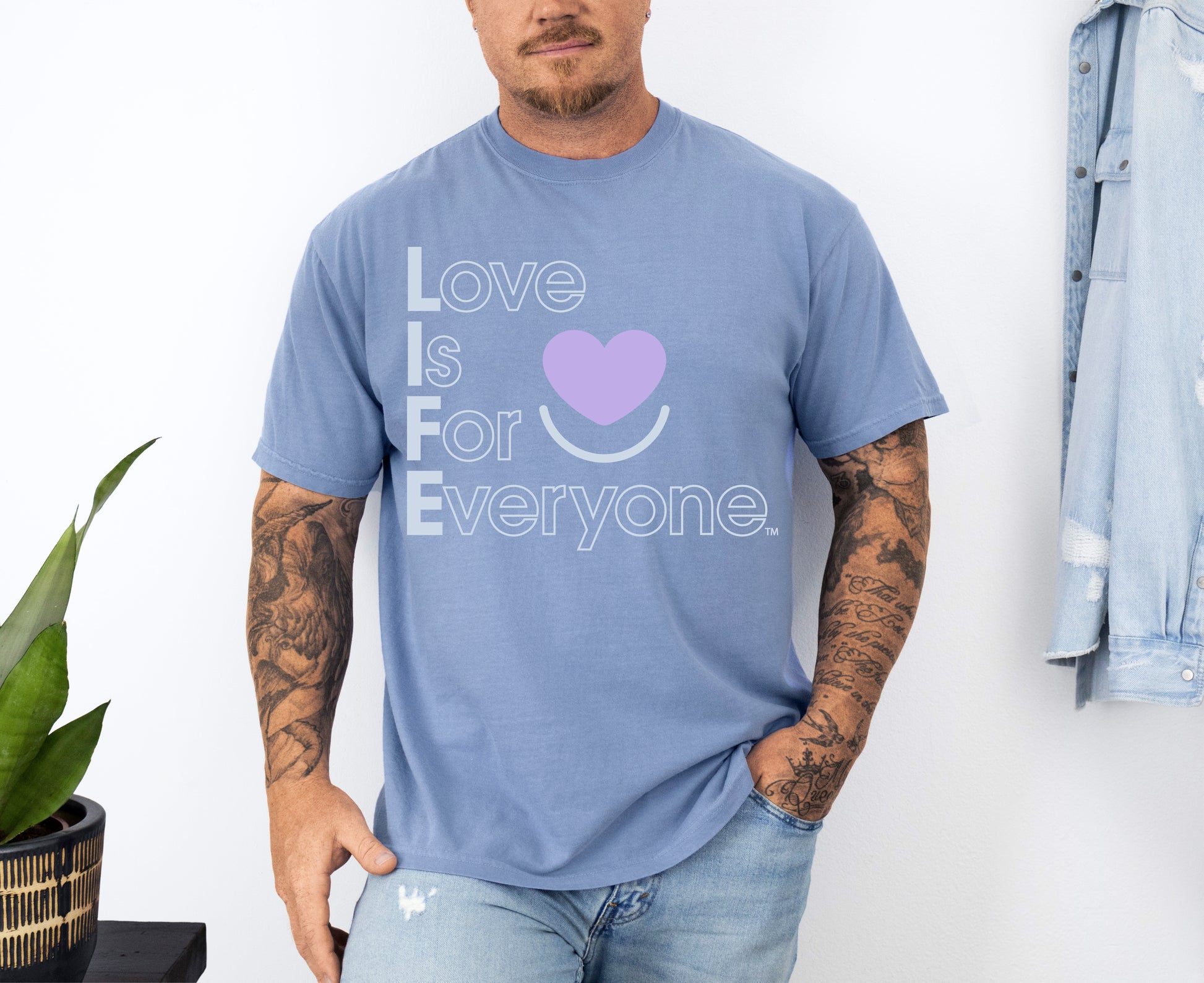 Man wearing Colorful Expressions washed denim Tee with “Love is for Everyone” postive message and heart smile