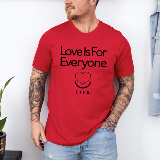 Man wearing men's Classic Tee in red, front view of smiling heart logo and message. 