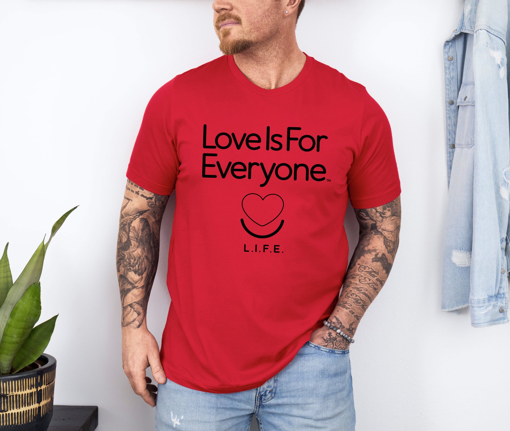 Man wearing men's Classic Tee in red, front view of smiling heart logo and message. 