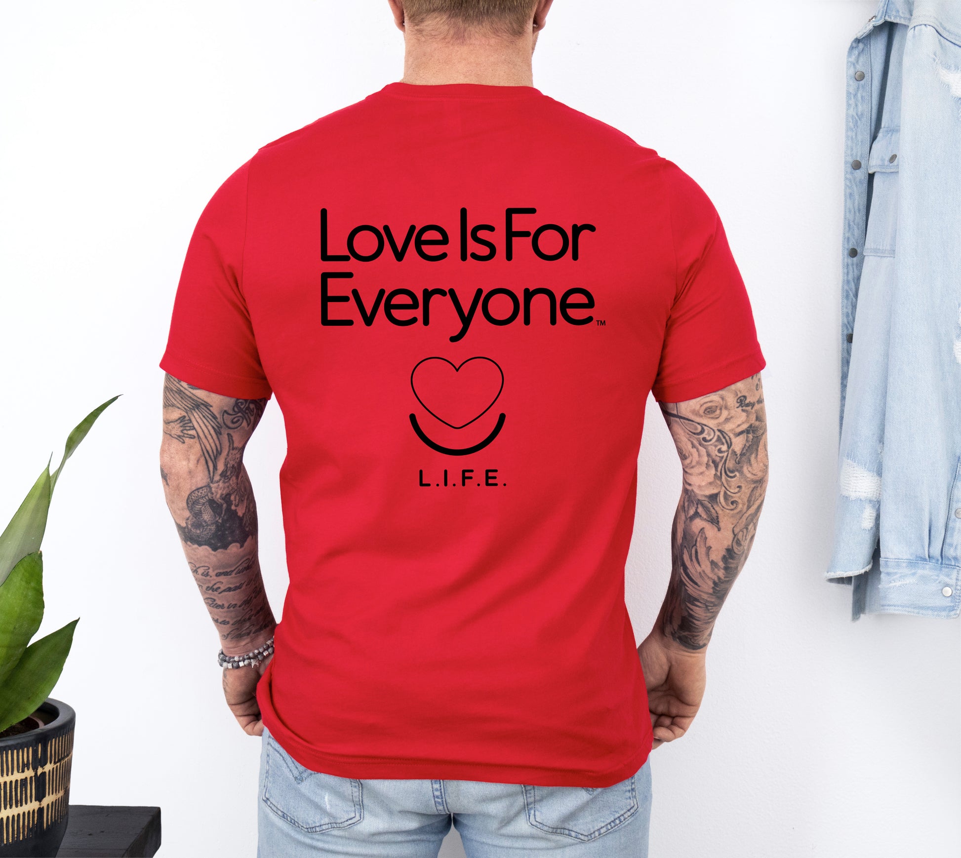 Man wearing men's Signature Tee in red, back view with "Love is for Everyone" graphic. 