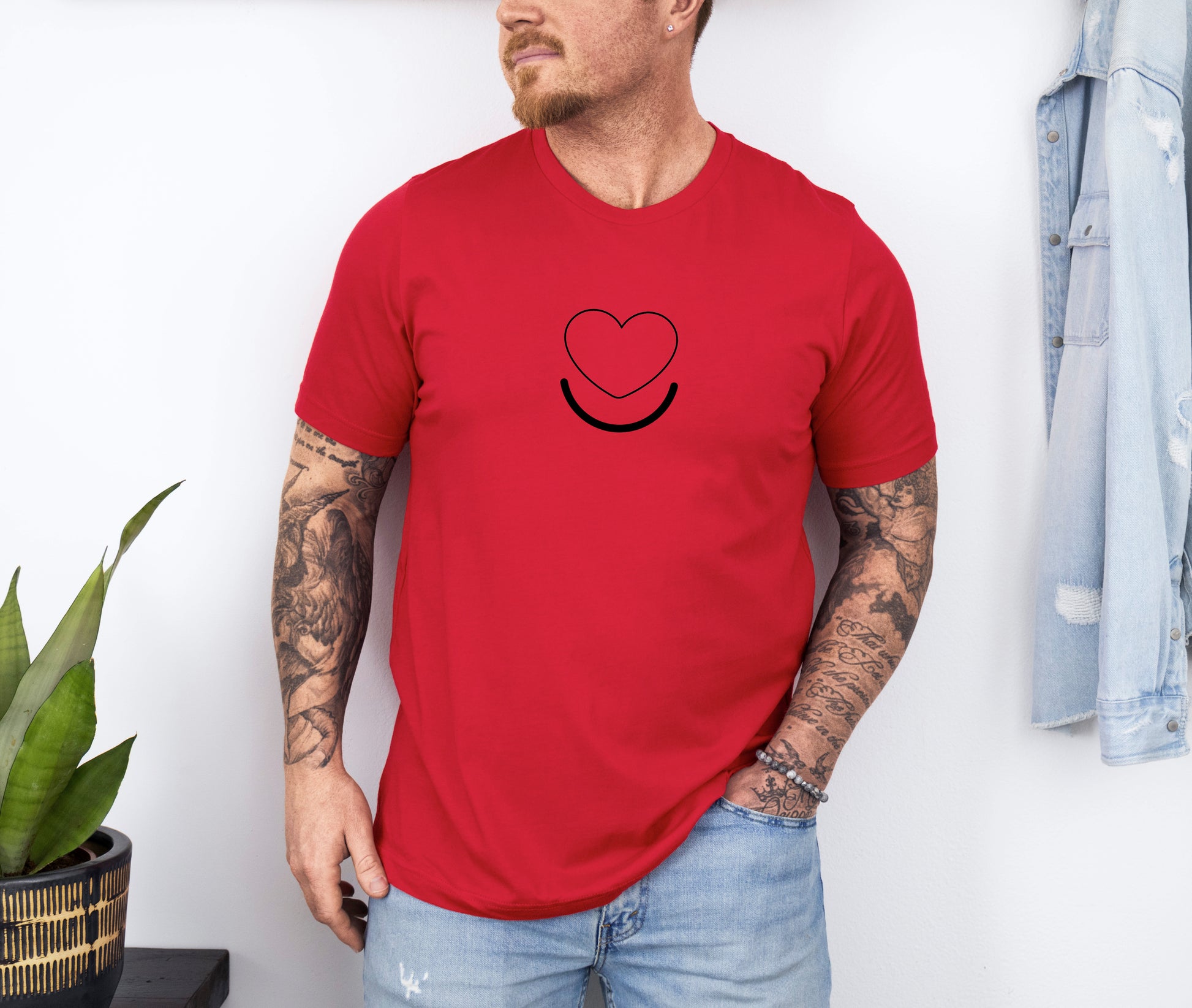 Man wearing men's Signature Tee in red, front view of smiling heart graphic.