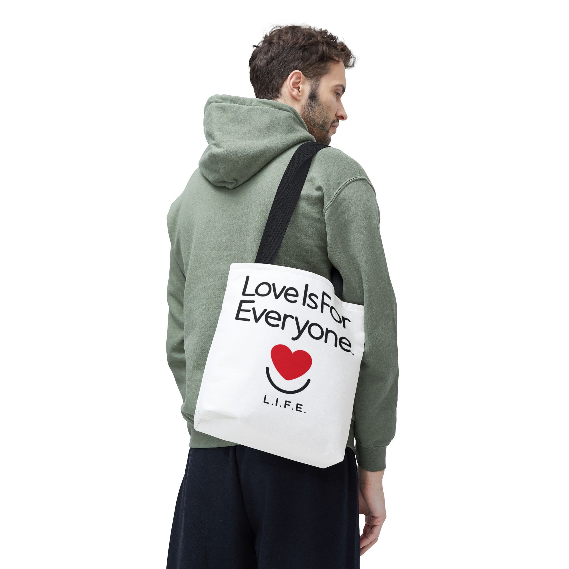 Man carrying white L.I.F.E. Signature Canvas tote with "Love is for Everyone" print and black handles. 