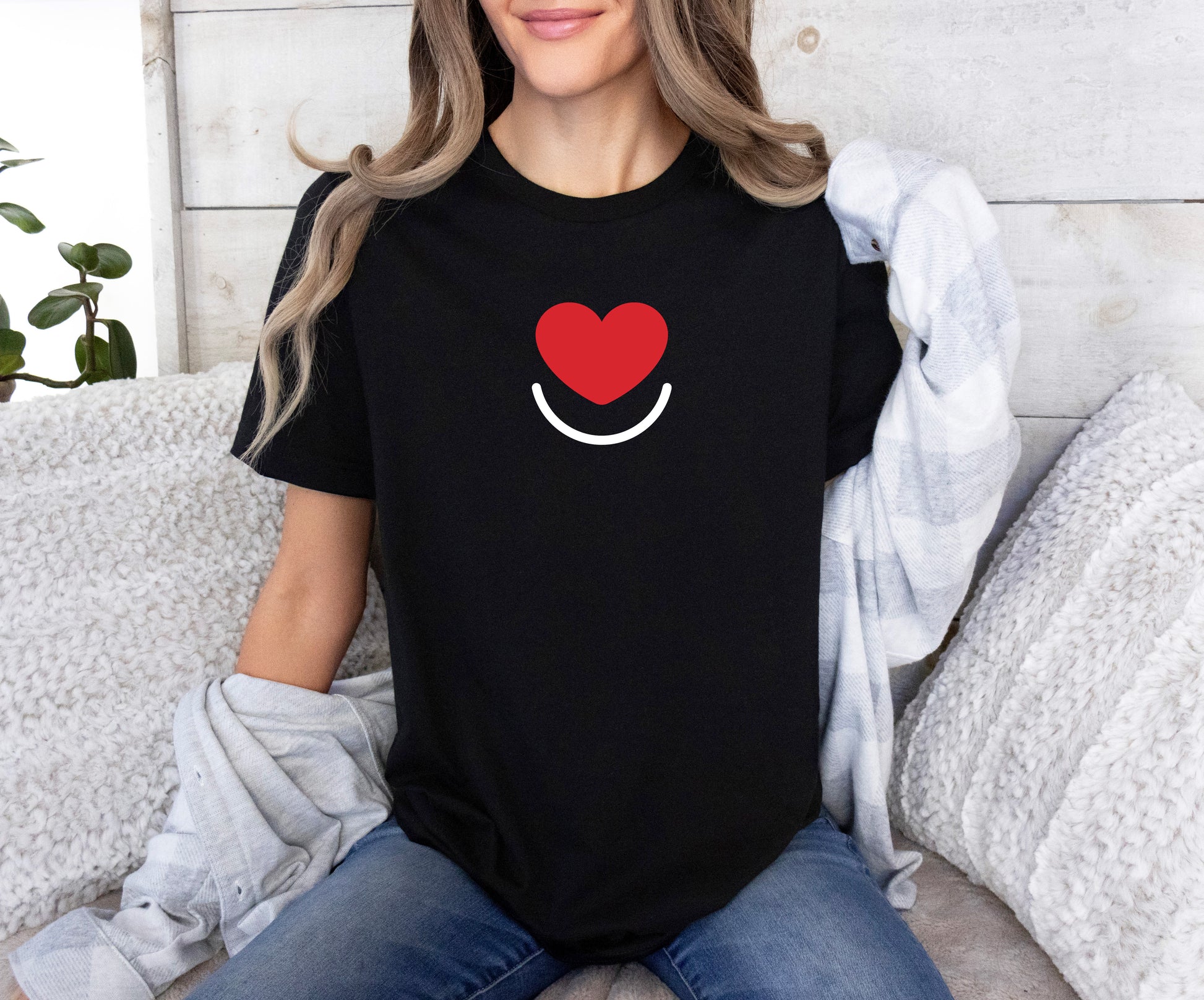 Woman in black L.I.F.E. Signature women's  graphic tee front with heart logo, seated casually. 