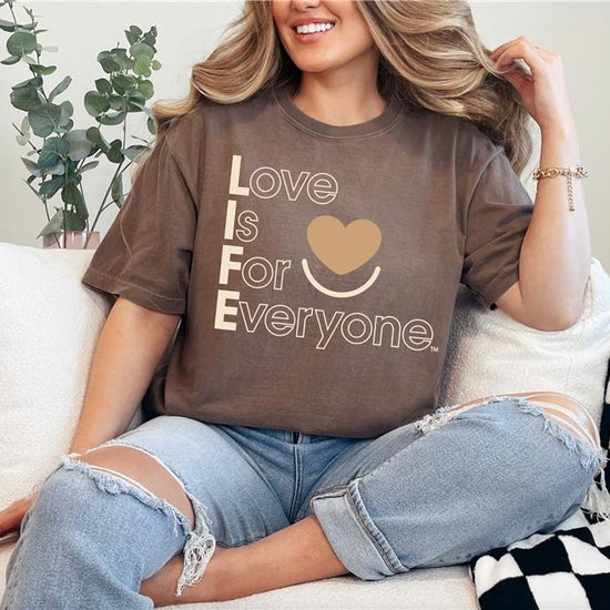 Woman wearing Espresso Comfort Colors®  tshirt with tonal "Love is for Everyone" heart design message.  