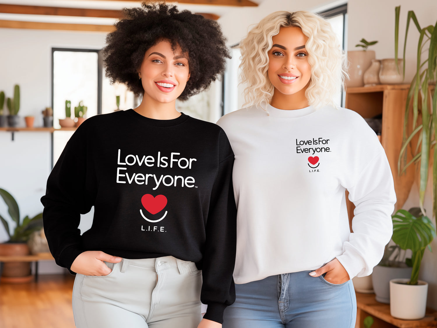 Women wearing black Classic crewneck and white Signature crewneck fleece with "Love is for Everyone" text and heart smile logos.