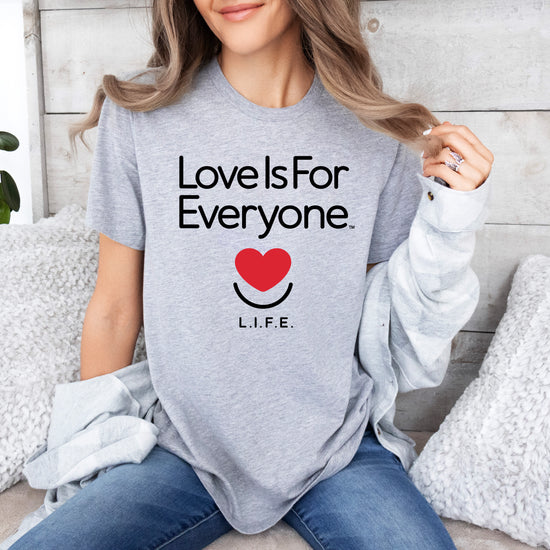 Woman in athletic heather L.I.F.E. "Love is for Everyone" Classic women's graphic tee, casual setting. 