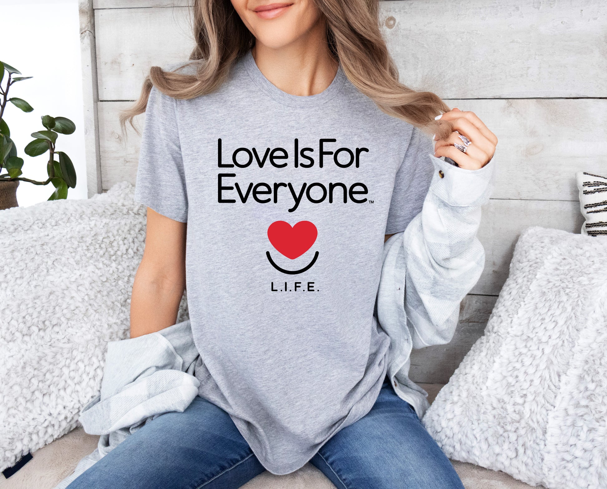 Woman in athletic heather L.I.F.E. "Love is for Everyone" Classic women's graphic tee, casual setting. 