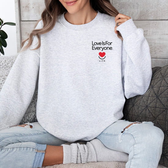 Woman wearing Subtly Stated crewneck ash with left chest logo “love is for everyone”. 