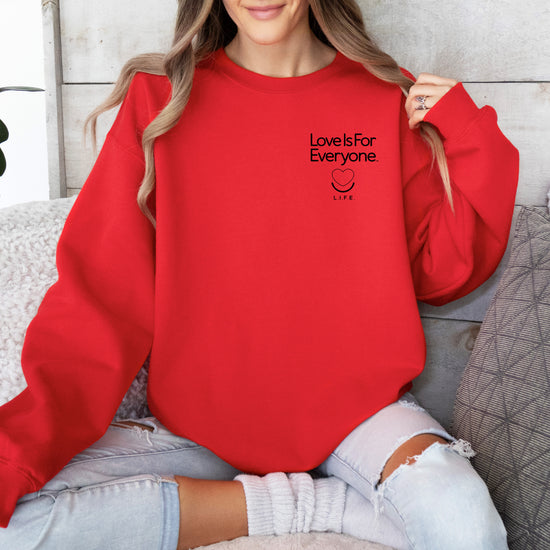 Woman wearing red L.I.F.E. Subtly Stated women's/unisex crewneck with left chest logo.