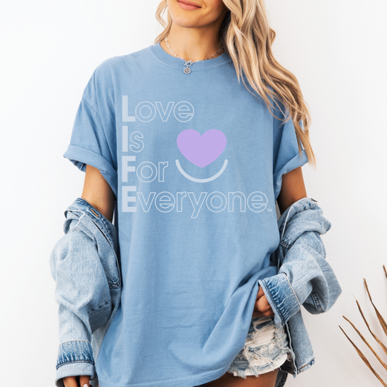 Woman wearing washed denim tee, rolled sleeves, "Love is for Everyone" design.