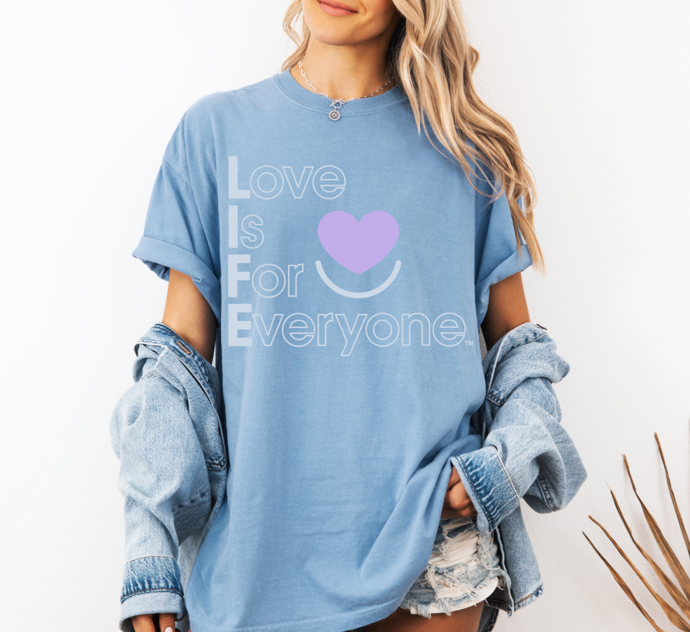 Woman wearing washed denim tee, rolled sleeves, "Love is for Everyone" design.